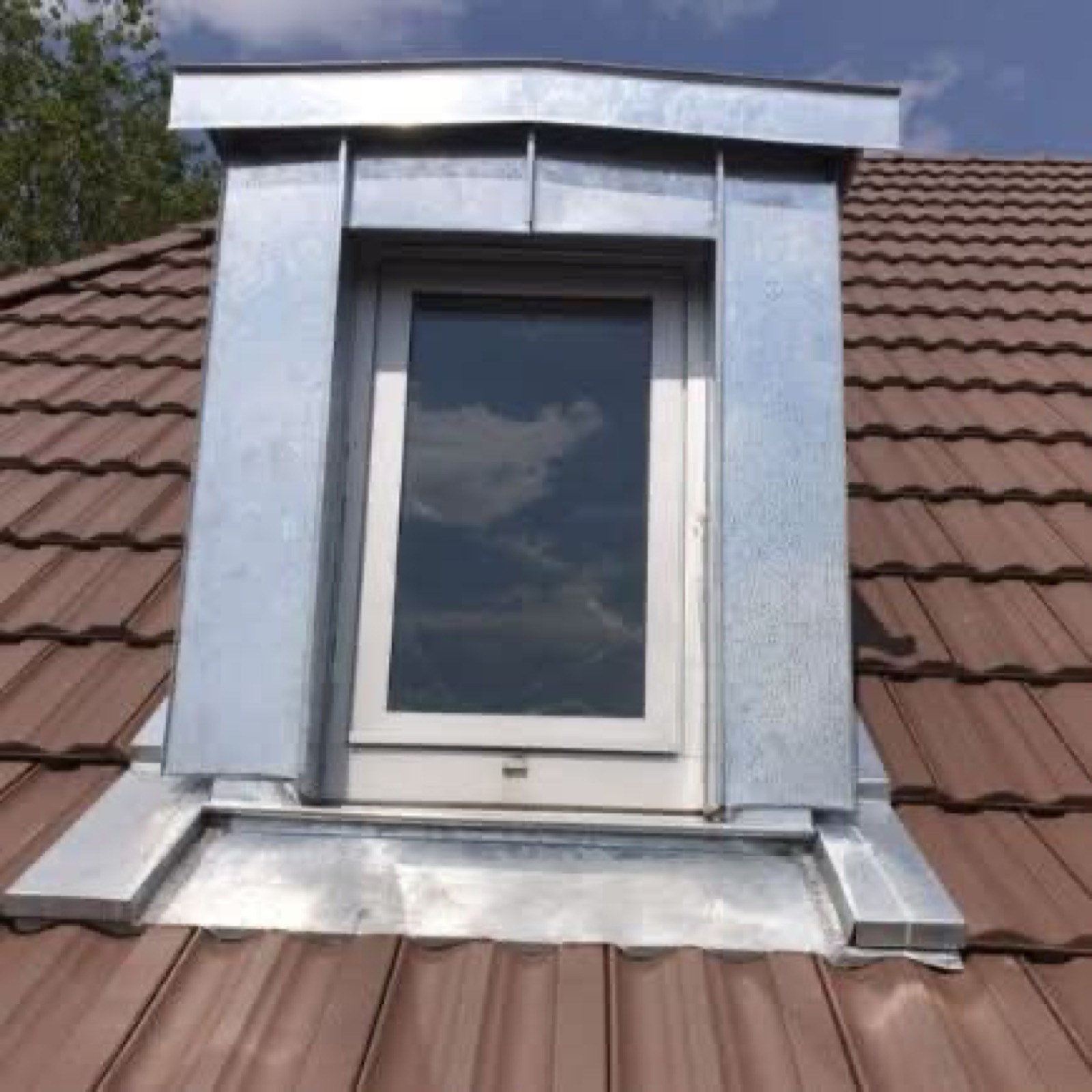 Zinc flashing and low-slope roofing detail around a finished dormer