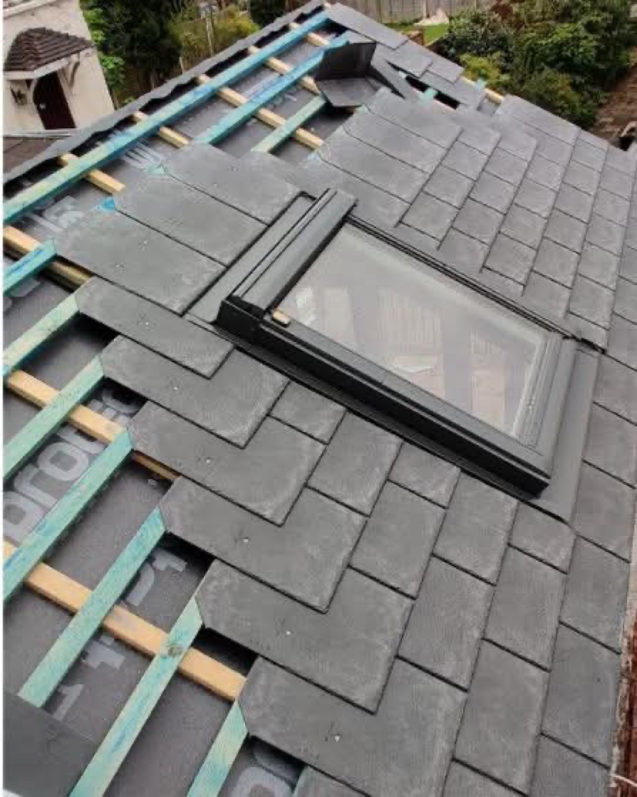 Roof tiling in progress around a newly installed skylight
